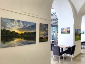 Blick in den Galeriebereich der Regionalbibliothek Weiden mit Ölbildern von Sonnenuntergängen